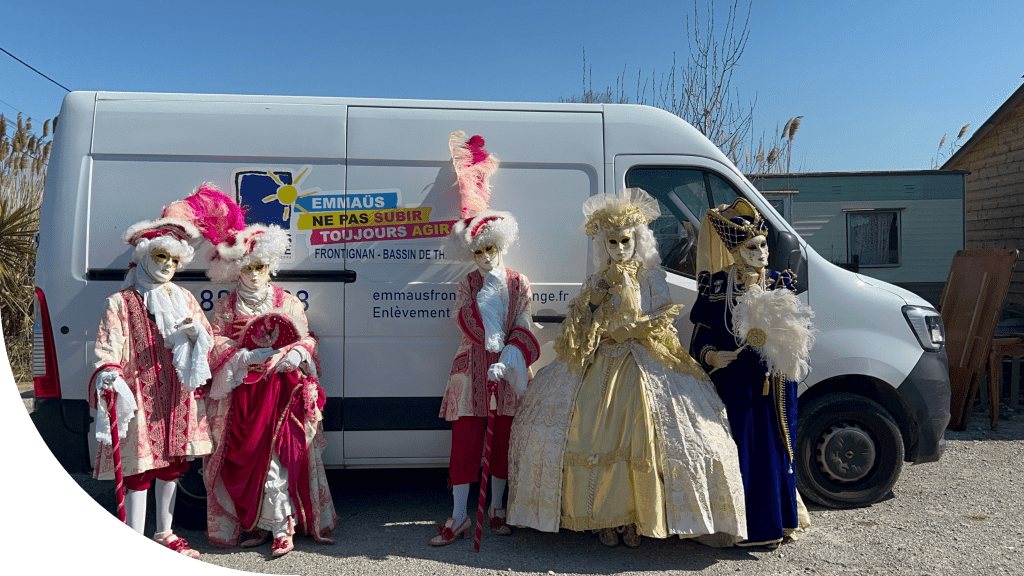 Cinq personnes portant des masques de style vénitien devant un bus Emmaüs