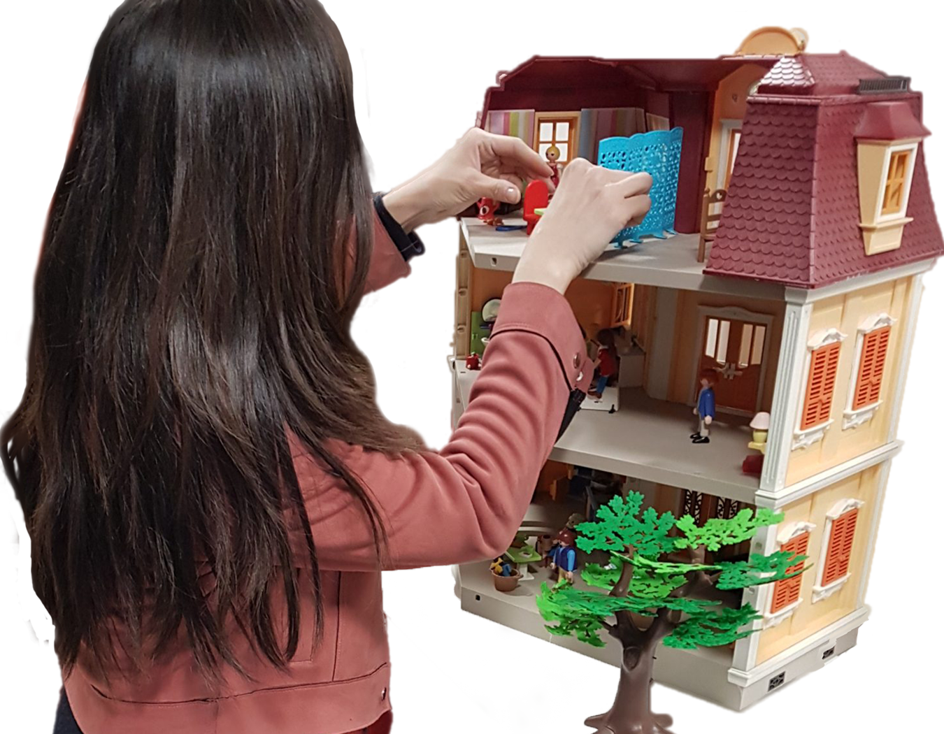Une femme se tient près d'une maison Playmobil